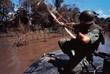 08 Dec 1967, Bassac River, South Vietnam --- A Navy lieutenant aims his flaming arrow at a hut across the river that conceals a Viet Cong bunker. --- Image by  Bettmann/CORBIS